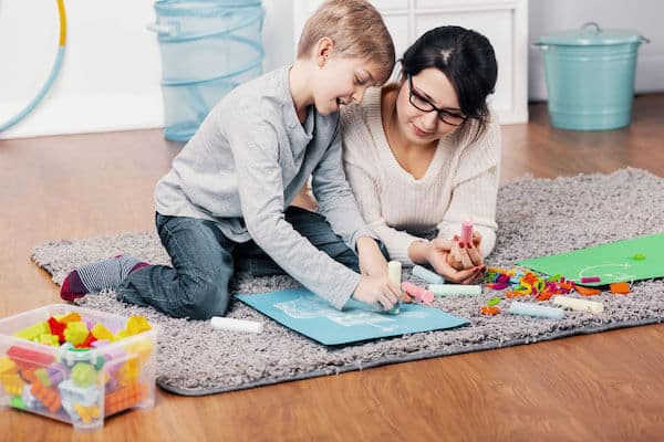 white mom with child on rug doing dot painting