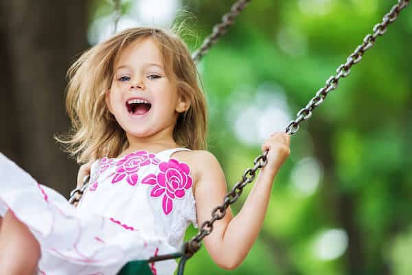 young white smiling girl on swing