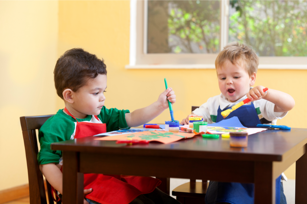 Young boys painting during an early intervention ABA therapy activity, illustrating how creative play supports growth.