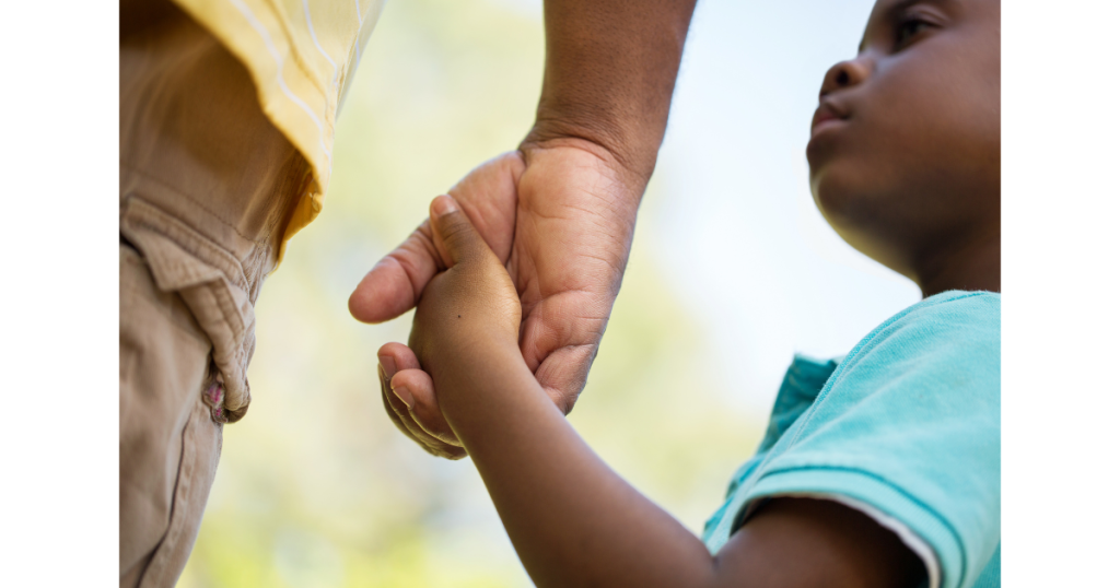 A parent holds a child’s hand, taking the step towards early diagnosis of autism.