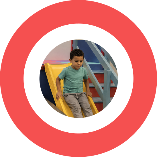 Young boy sliding down a yellow indoor slide at a play area.