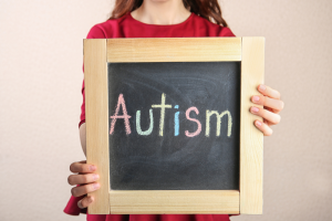 Young girl holding chalkboard sign that says ‘autism’
