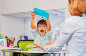 Child tipping a pencil case, as a child with autism might throw things in frustration. 
