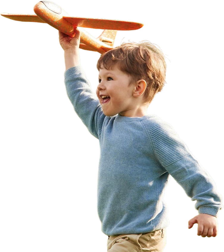 blog-hero Young boy in a blue sweater smiling while holding up a toy airplane.
